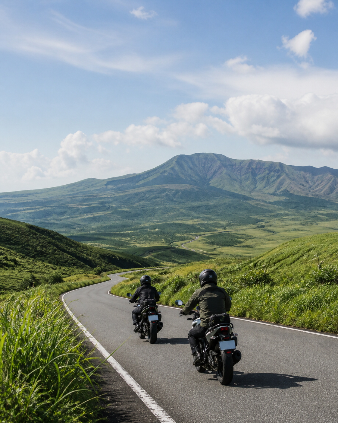 阿蘇の草原と山並みを走るツーリング風景